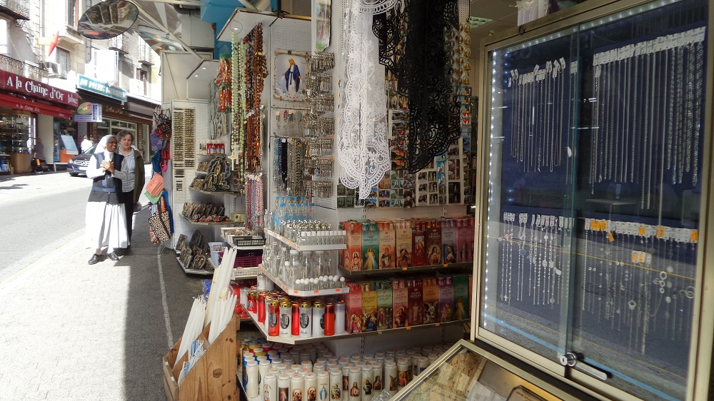 The main street of Lourdes is filled with trinket shops. Source: Village to Villa